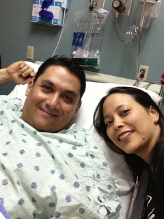 man in a hospital bed with a woman leaning in for a photo